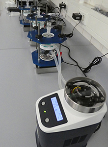 Abbildung 5 zeigt den Versuchsaufbau und verwendeten Geräte im Labor zur Permeationsprüfung bei PSA-Schutzhandschuhen.