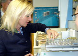 Die Ministerin betrachtet einzelne kleine Probengefäße im Labor.