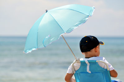 Junge mit Sonnenschirm am Strand