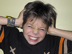 Foto: Junge verzieht das Gesicht und hält sich die Ohren zu