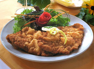 Das Bild zeigt einen Teller mit einem appetitlich aussehenden panierten Schnitzel zusammen mit einer kleinen Salatgarnitur