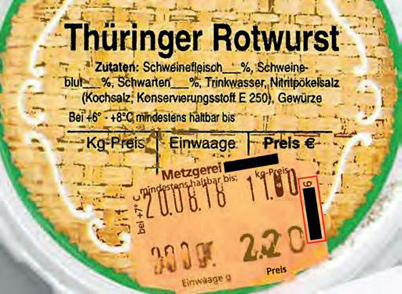 Das Bild zeigt das Etikett einer Probe, die missbräuchlich als Thüringer Rotwurst bezeichnet wurde. Dies ist hier bereits daran zu erkennen, dass eine Preisschild der herstellenden Metzgerei mit deren Adresse aufgeklebt ist, das den Sitz der Metzgerei in Lauf im Landkreis Nürnberger Land angibt.