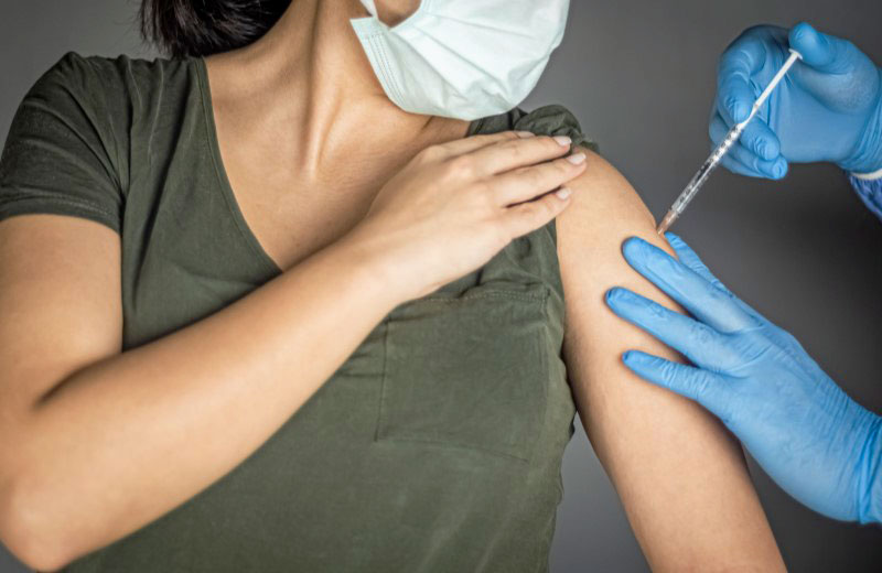 Impfstoff wird mit Spritze in Oberarm injiziert.