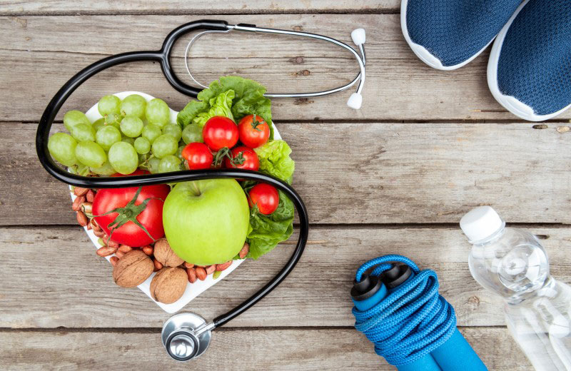 Herzförmige Schale mit Früchten, Gemüse, Walnüssen und Stetoskop